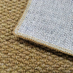 Close-up of doormat corner showing beige pile and white gridded underside.