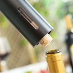 Electric wine opener tip inserted into a cork at the top of a bottle