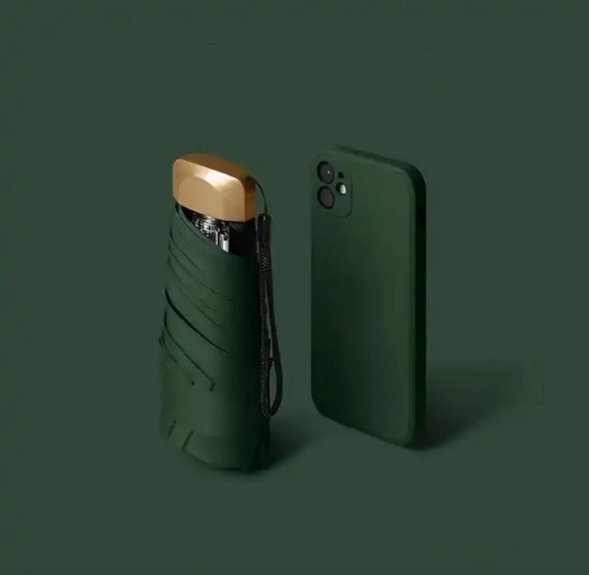 Green mini travel umbrella, folded pocket size with carry strap and gold cap.