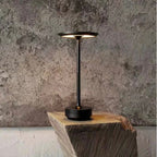 Dark rechargeable table lamp on wooden stump with warm glowing top