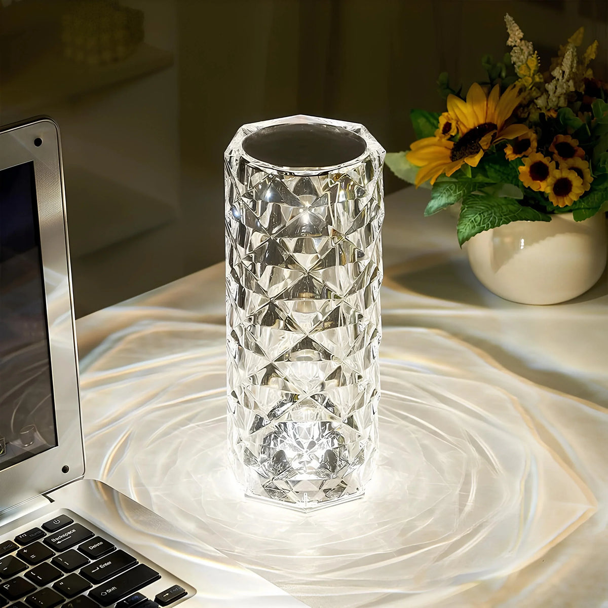 Clear faceted crystal table lamp with warm white glow, top opening and cylindrical body.