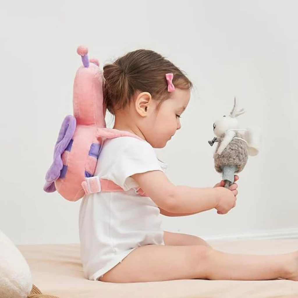 Pink padded head protector backpack with adjustable straps on a baby