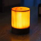 Compact cylindrical LED night light, woodgrain sides, warm glow over black base