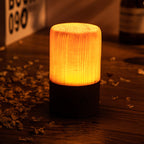 Cylindrical woodgrain LED night light on dark base with warm amber glow