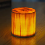 Woodgrain cylindrical LED night light with warm glow and black base