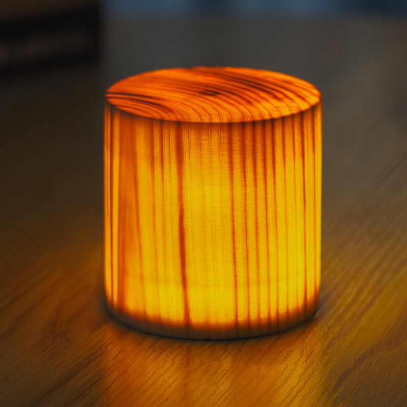 Woodgrain cylindrical LED night light with warm glow and black base