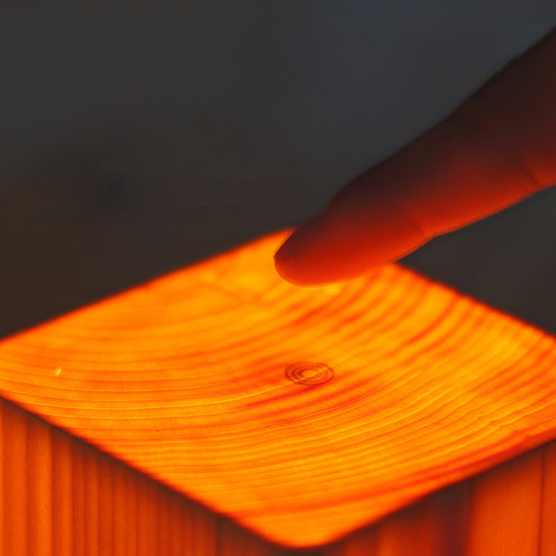 Touch top of a wood-look LED night light with warm glowing surface