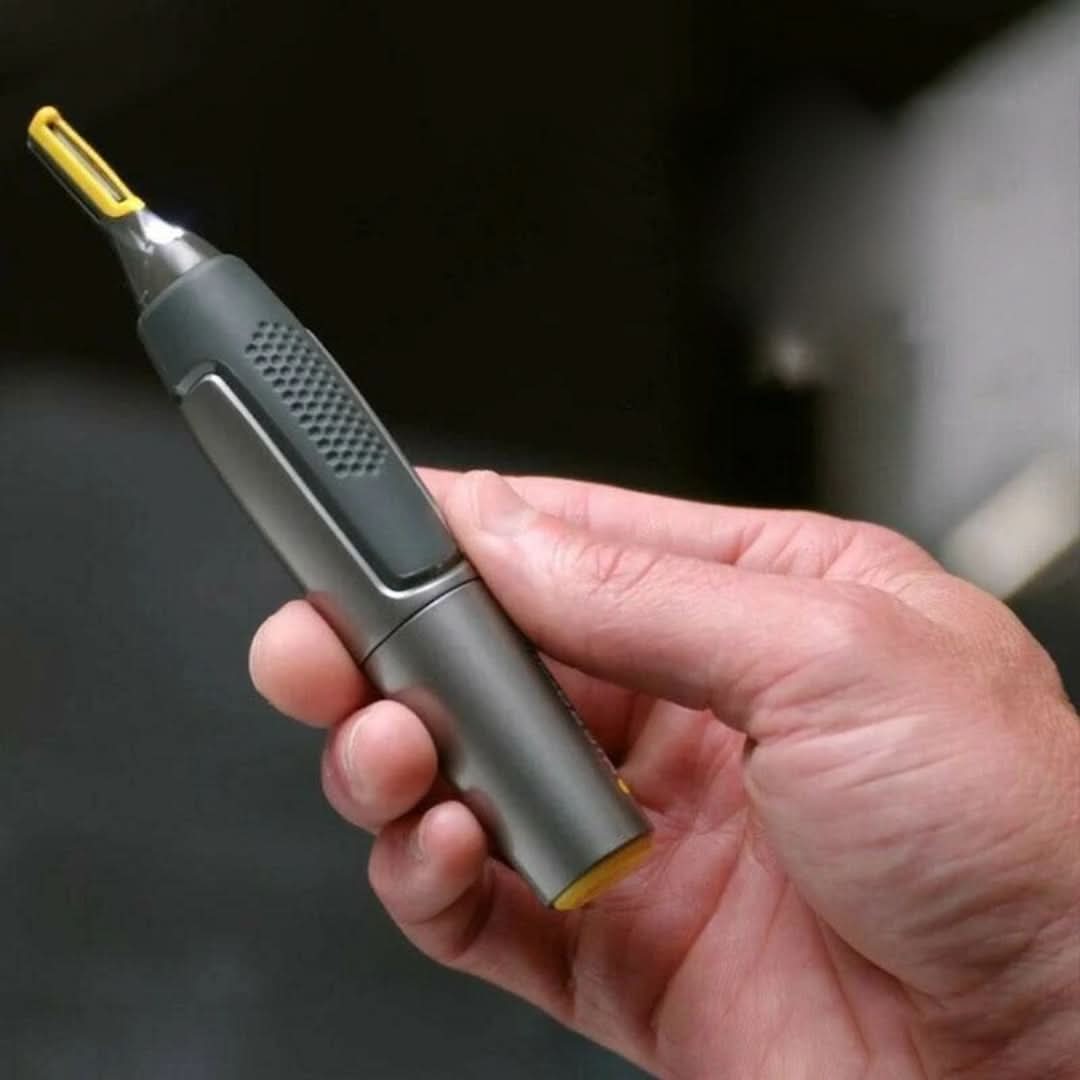 Hand holding cordless trimmer with yellow cutting head, dark gray textured grip