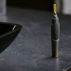 Cordless detail trimmer standing upright, black body with textured grip and yellow tip