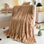 Bubble-texture fleece blanket in tan brown with ridged bubble pattern, draped on couch