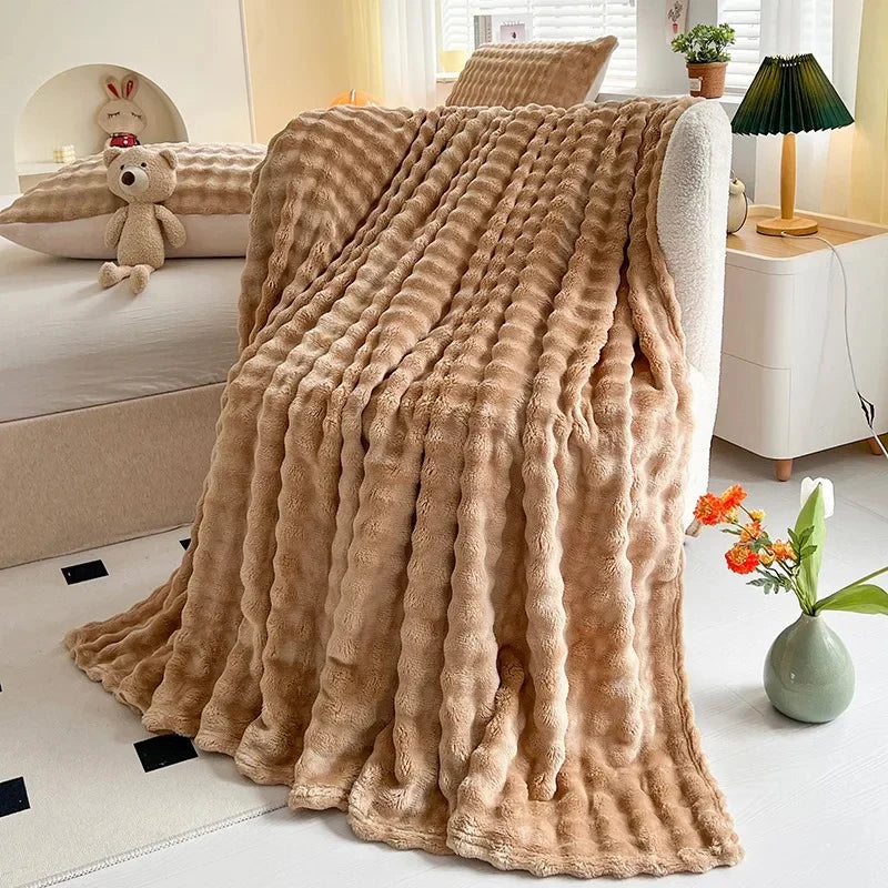 Bubble-texture fleece blanket in tan brown with ridged bubble pattern, draped on couch