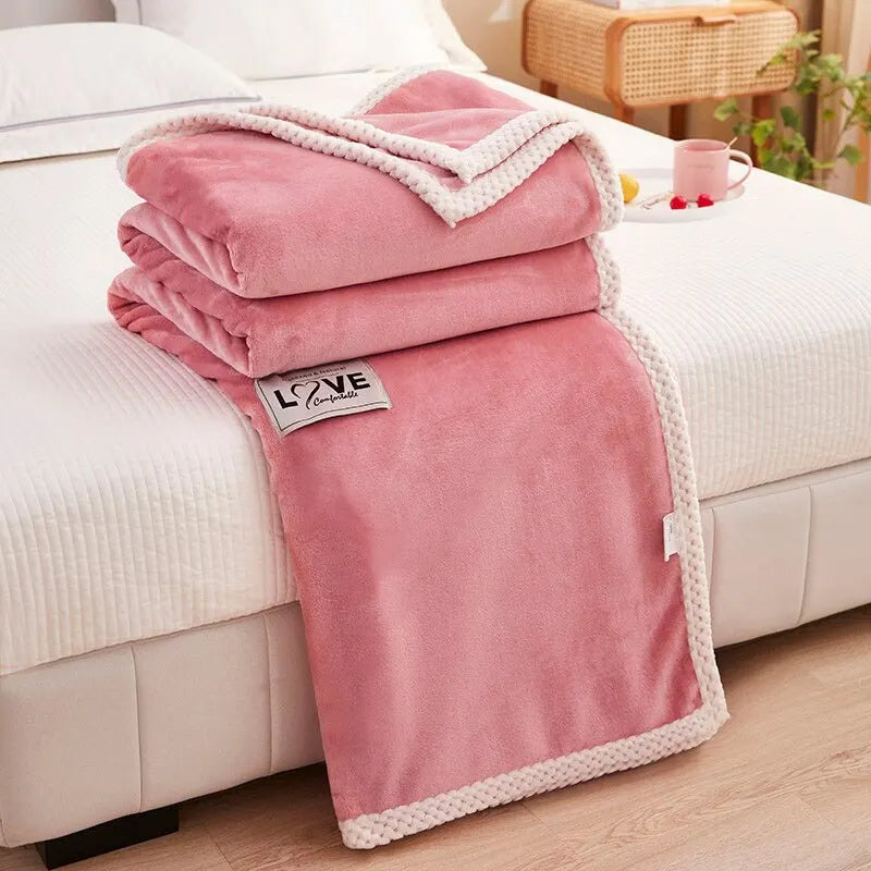 Pink fleece throw blanket folded with white dotted edge trim and stitched label