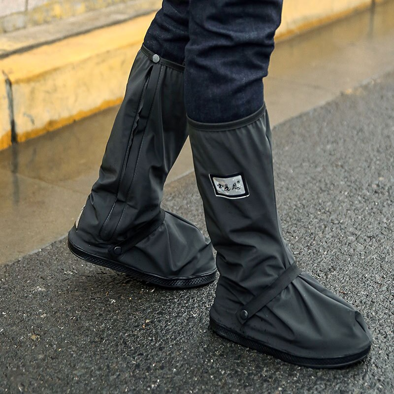 Black overshoe covers worn over shoes, with square logo patch and snap tabs