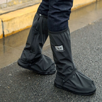 Black overshoe covers worn over shoes, with square logo patch and snap tabs