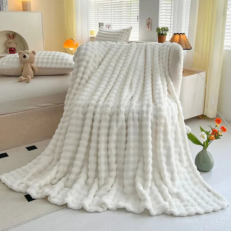 Bubble-texture fleece blanket in white with ridged bubble pattern, draped on couch