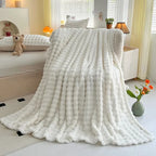 Bubble-texture fleece blanket in white with ridged bubble pattern, draped on couch