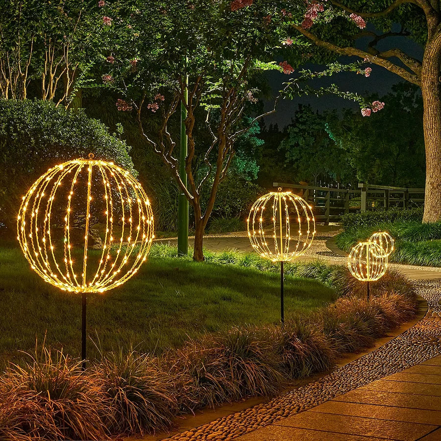 Warm white LED light-up wire sphere decorations on stakes in a garden