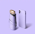 Lavender mini travel umbrella, folded pocket size with carry strap and gold cap.