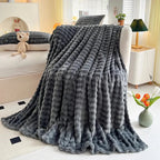 Bubble-texture fleece blanket in dark gray with ridged bubble texture, spread on bed