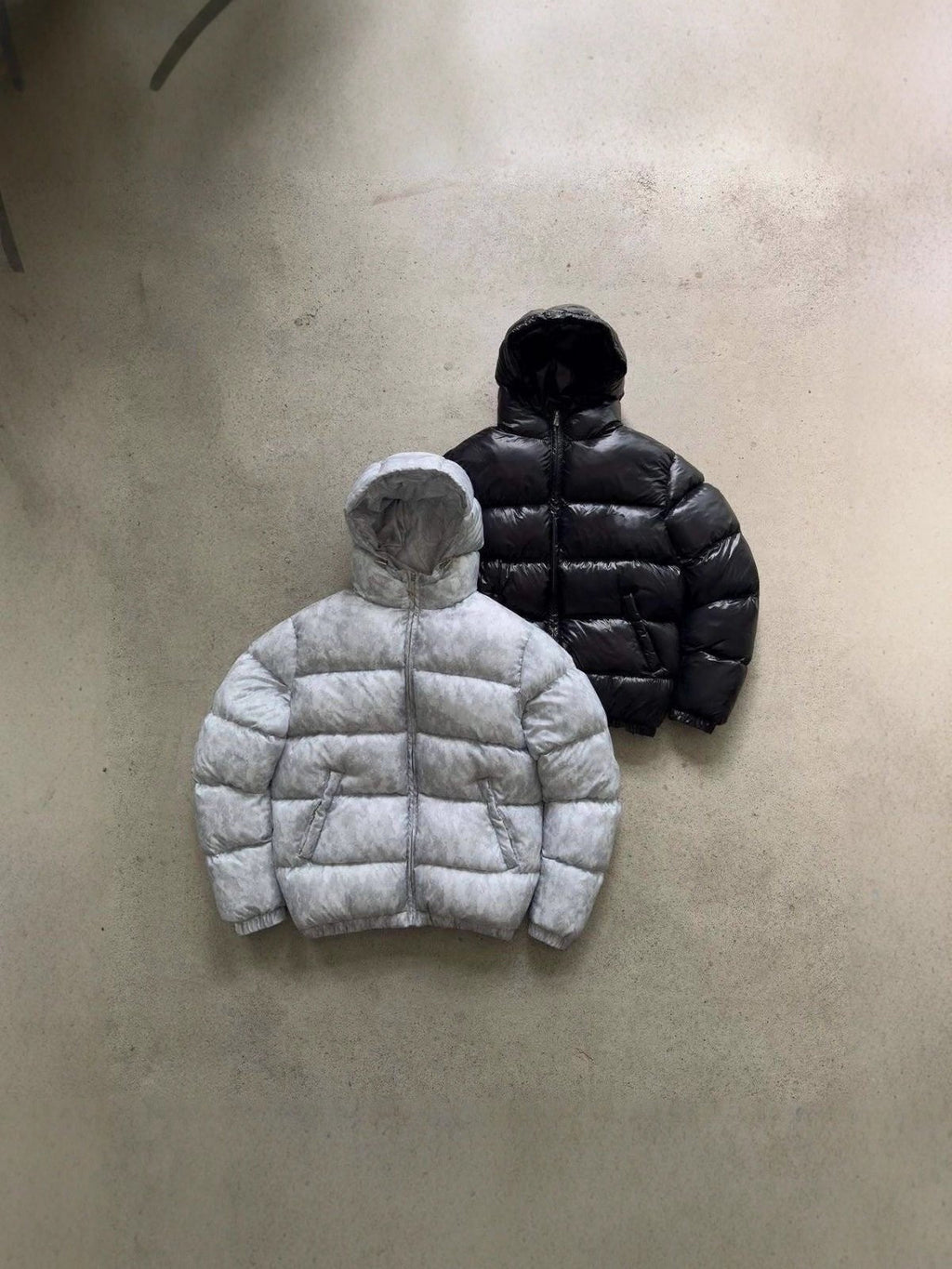 Hooded quilted puffer jackets in gray and black, two jackets laid out