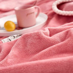 Close-up of pink plush fleece blanket with soft textured surface and white stitched edge