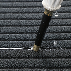 Black doormat texture close-up with dense ribbed stripes for scraping dirt