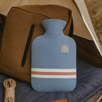 Light blue knit hot water bottle cover with white and tan stripe bands, stopper
