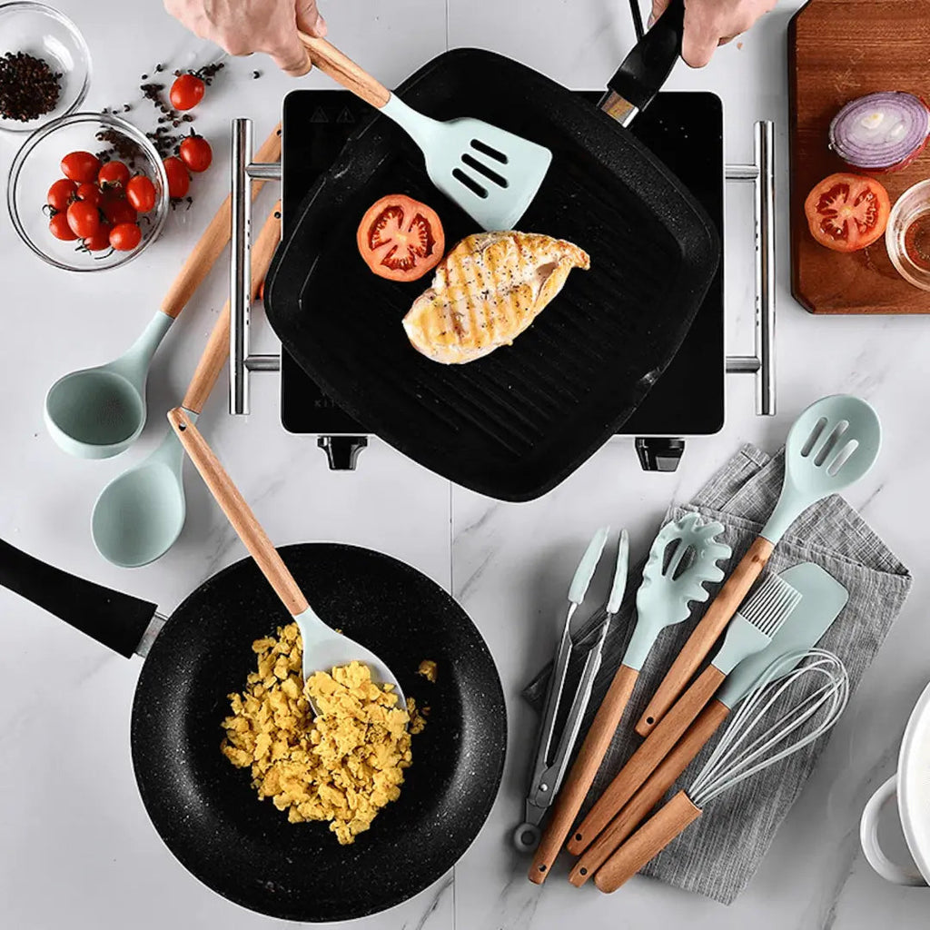 Teal silicone cooking utensil set with wooden handles, spatulas, ladles, and a whisk