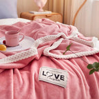 Pink plush fleece blanket with white rope-style trim and LOVE label on top