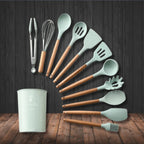 Mint green silicone kitchen utensil set with wooden handles, ladles and spatulas in cup