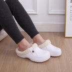 White plush-lined slip-on clogs on a person with bare feet