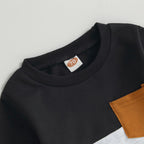 Baby Jogger sweatshirt detail: black top with orange label and tan pocket panel at chest.