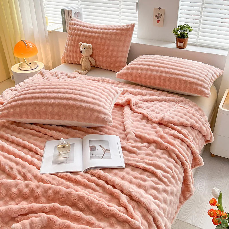 Bubble-texture fleece blanket in soft coral pink with ridged bubble pattern, on couch