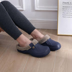 Navy slip-on clogs with plush gray lining, worn indoors on wood floor