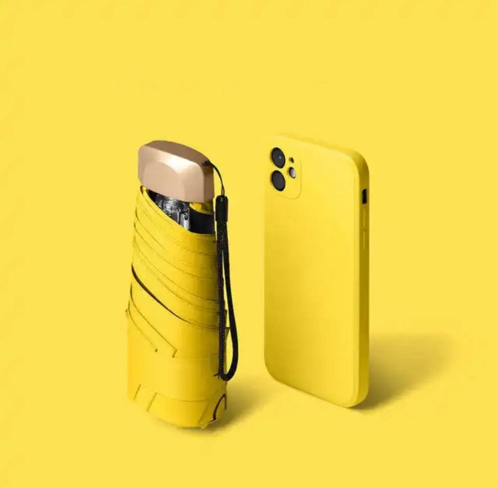Yellow mini travel umbrella, folded pocket size with carry strap and gold cap.