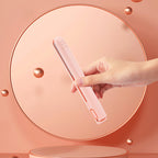 Mini 2-in-1 travel curling and straightening iron in light pink, held upright in hand.