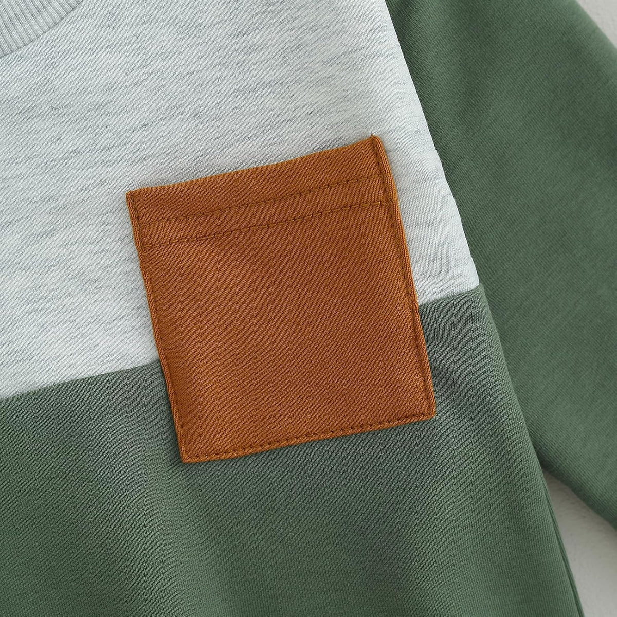 Brown fabric pocket patch on a light blue sweatshirt front