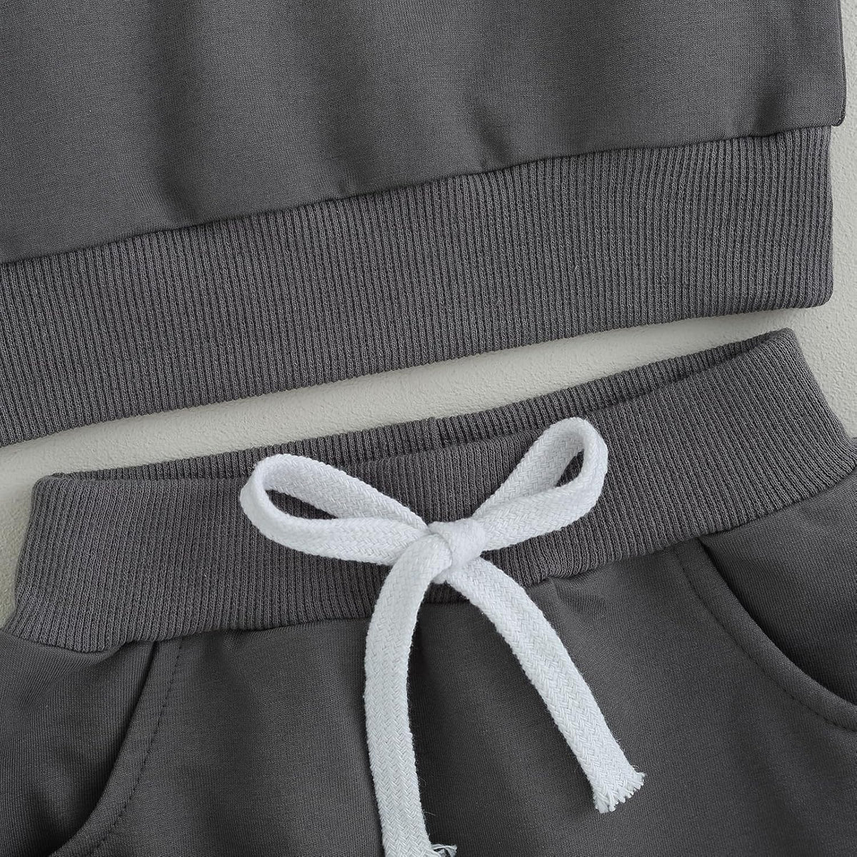 Gray pants waistband with white drawstring and ribbed pant cuffs