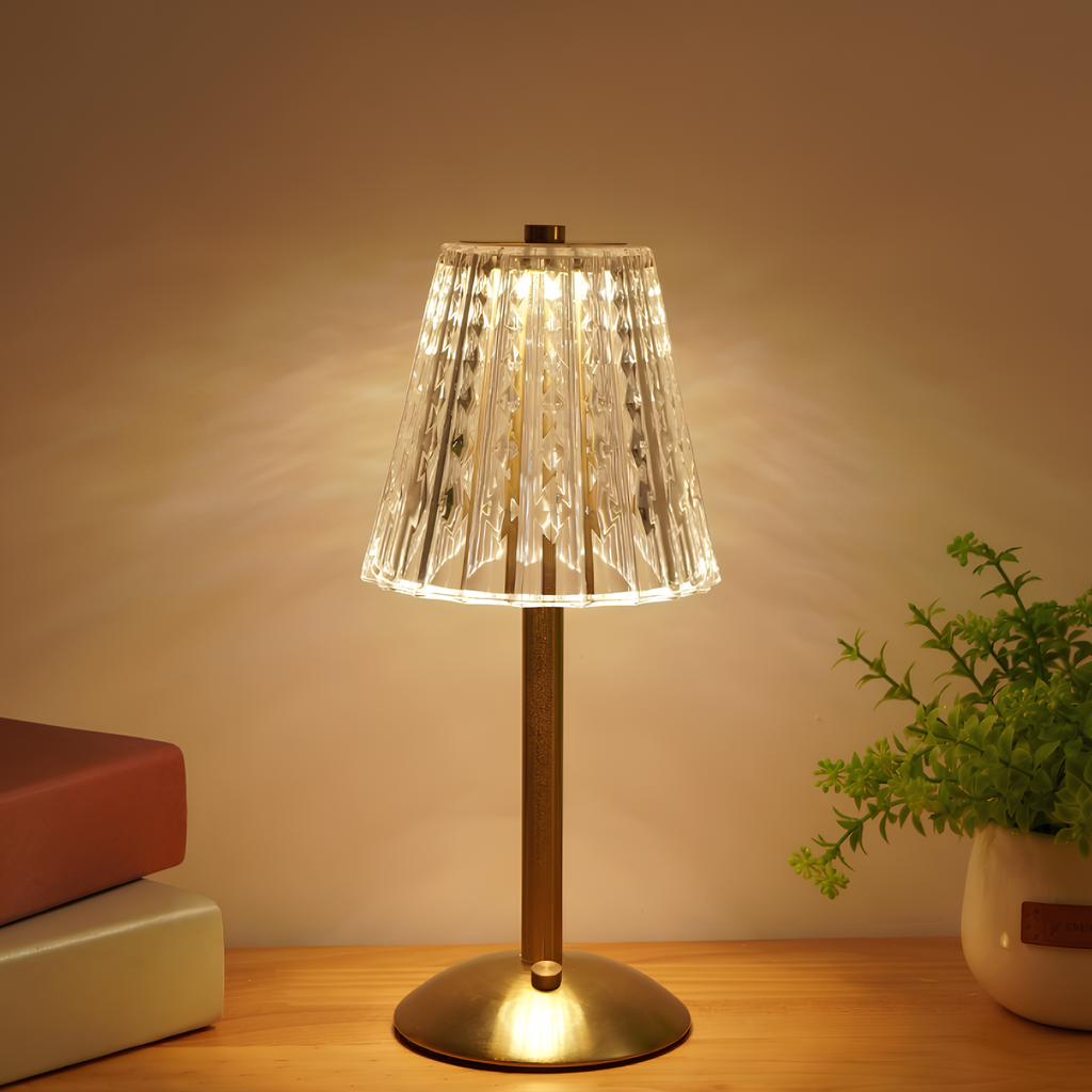 Gold stand table lamp with clear crystal ribbed shade, warm light glowing.