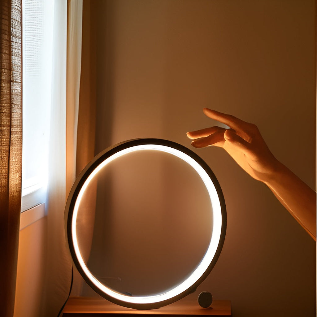 Minimalist round LED table lamp with touch control, hand reaching toward glowing halo ring