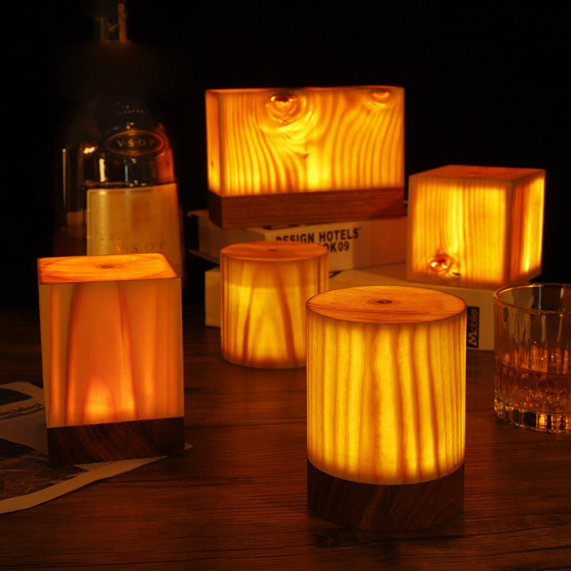 Wood-look LED table lamps with warm glowing shades in cylinder, square, and rectangle shapes