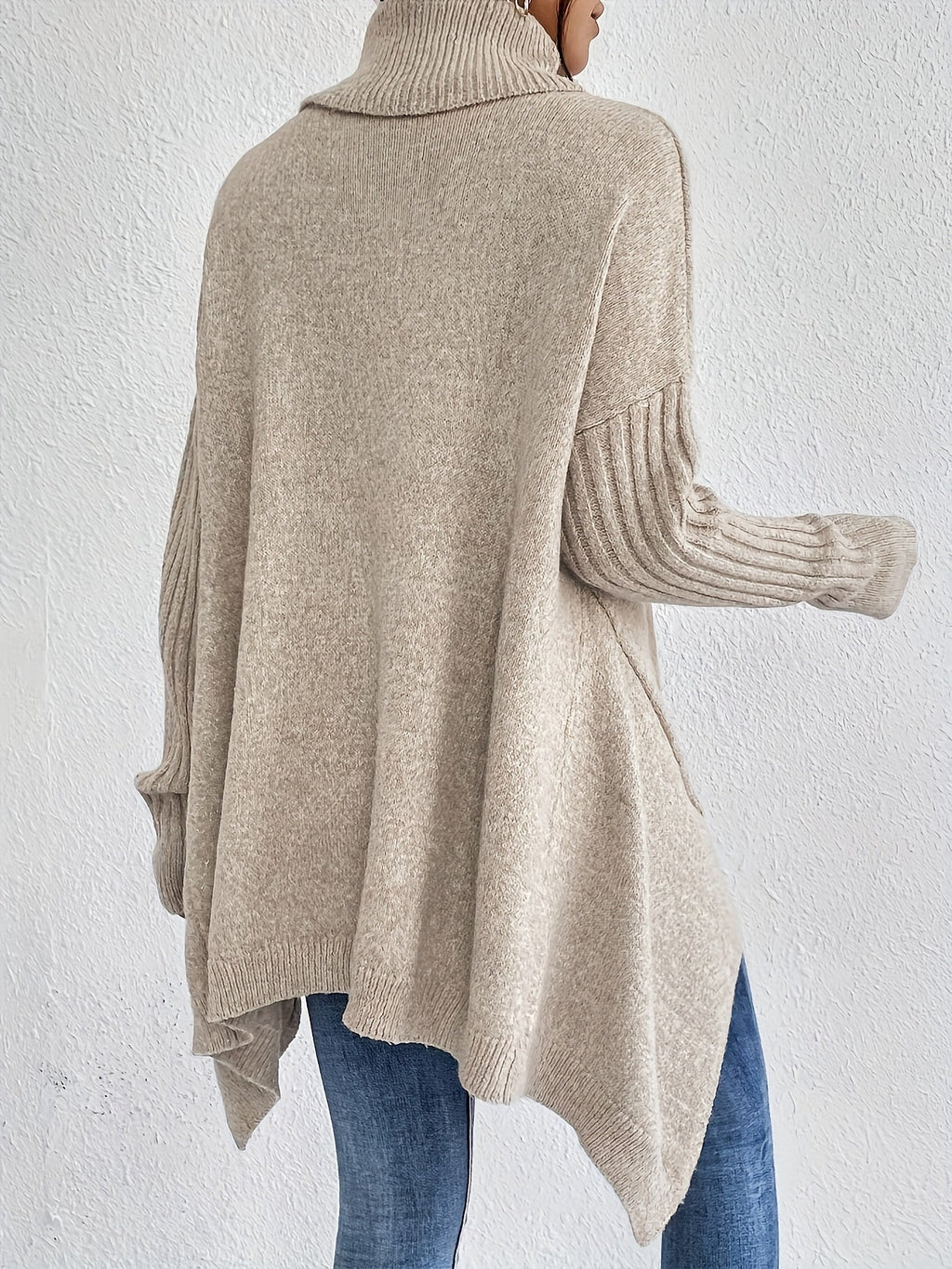 Back view: women’s loose turtleneck sweater, beige knit with ribbed cuffs.