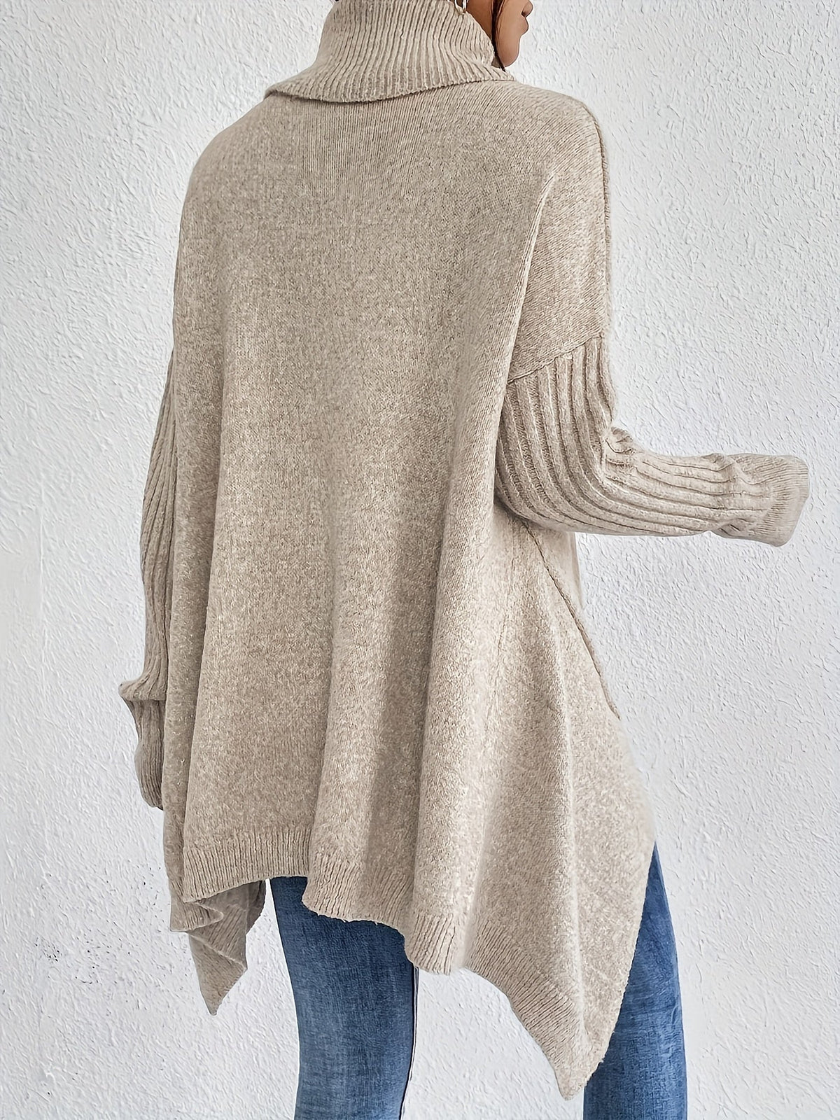 Back view: women’s loose turtleneck sweater, beige knit with ribbed cuffs.