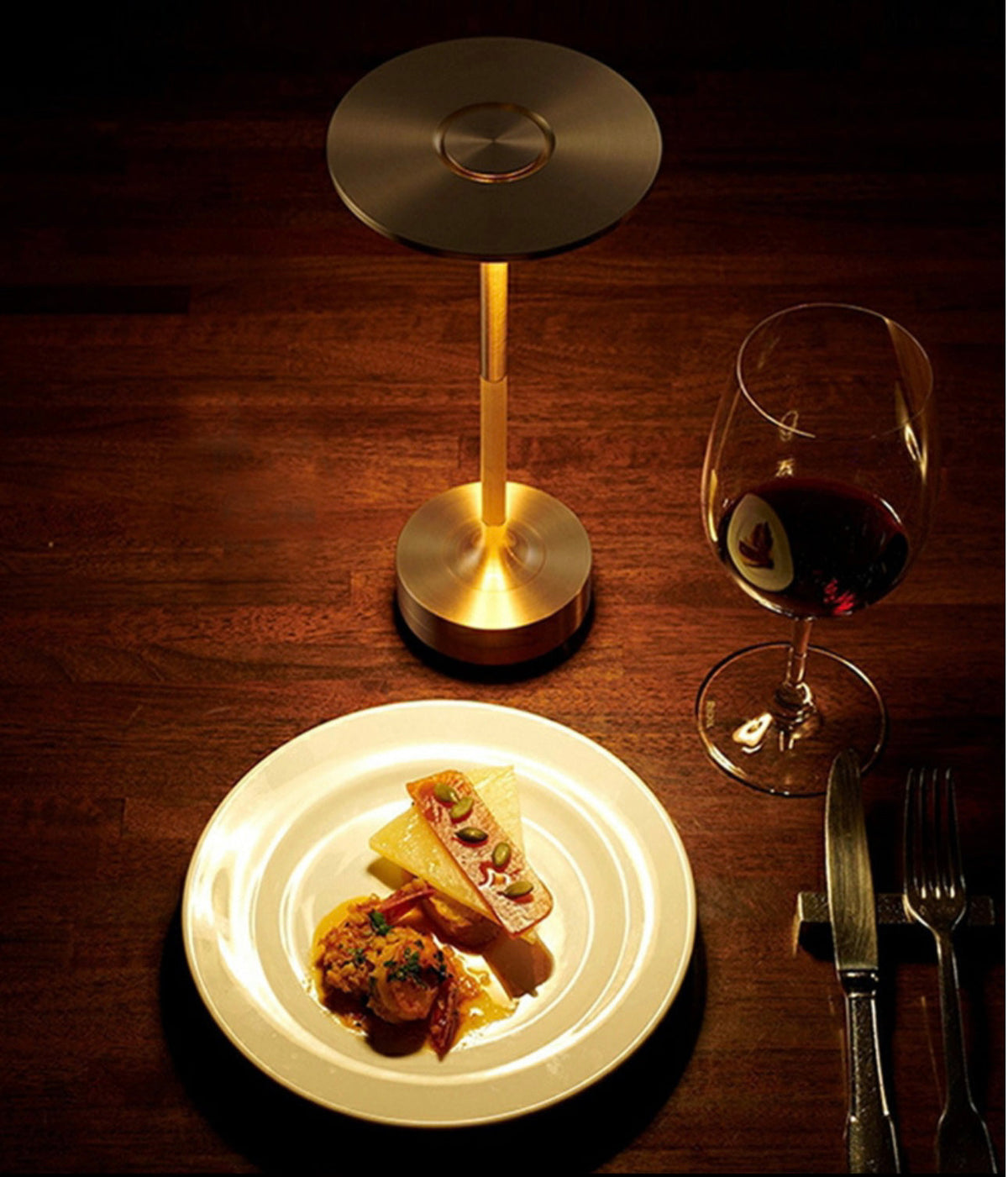 Cordless LED table lamp with bronze stem and round top shade, warm light on