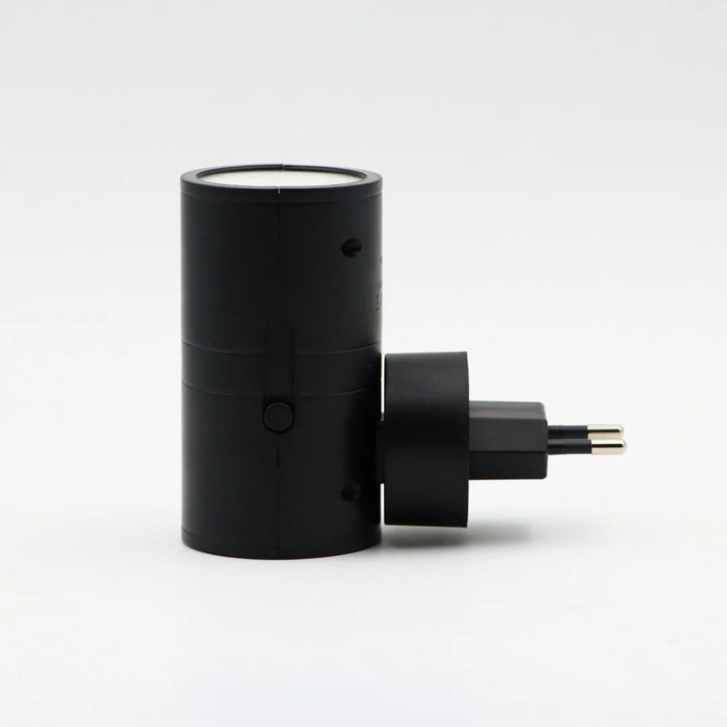 Black cylindrical plug-in LED wall light with two-prong plug and warm top glow