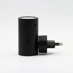 Black cylindrical plug-in LED wall light with two-prong plug and warm top glow