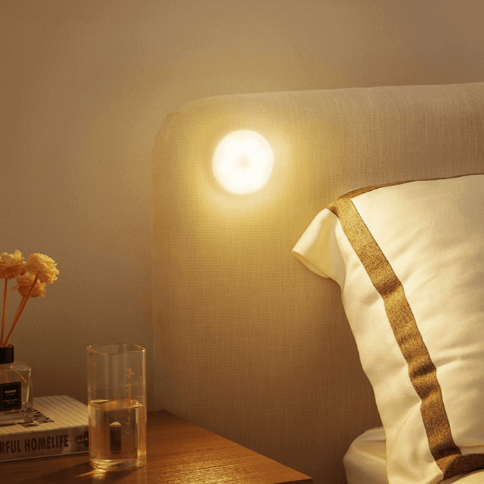Warm-white LED motion sensor light on wall beside bedside area, glowing