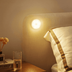 Warm-white LED motion sensor light on wall beside bedside area, glowing