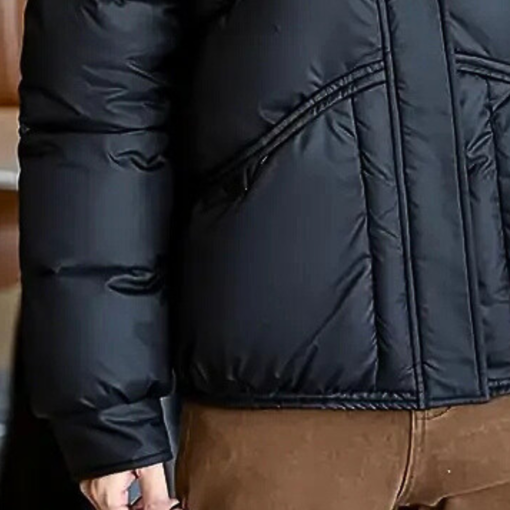 Women’s black puffer jacket close-up of side quilting, zipper seam, and cuff