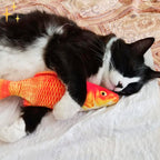 Plush cat fish toy with orange body and yellow scales, black-and-white cat playing